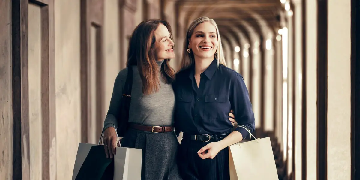 Due donne che hanno fatto acquisti. L’immagine trasmette la semplicità e la sicurezza dei pagamenti quotidiani.